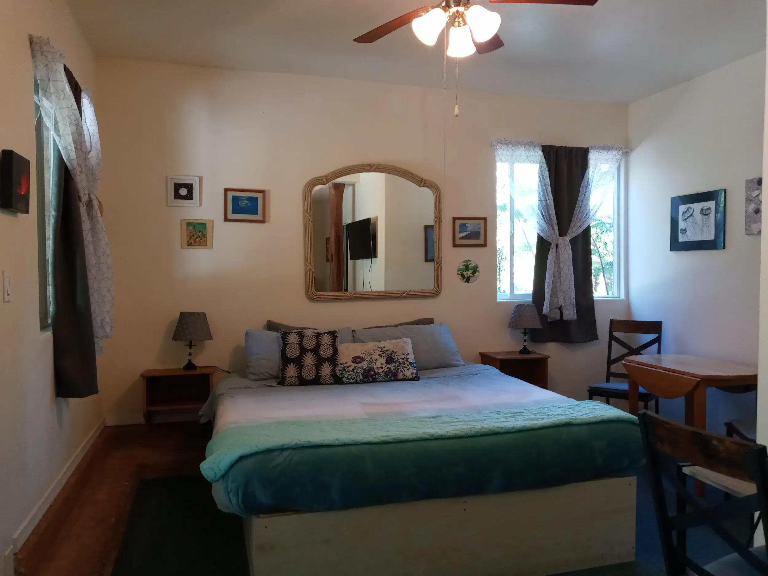 Static hero view of Room 2 — The Collective Retreat at Aloha Crater Lodge, showing the two-queen bedroom with private kitchenette and sliding glass door opening to the rainforest-facing patio in Volcano Village, Hawai'i.